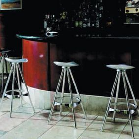 Tres taburetes de bar están alineados frente a una barra.