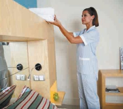 Una mujer está parada en un dormitorio sosteniendo una toalla.