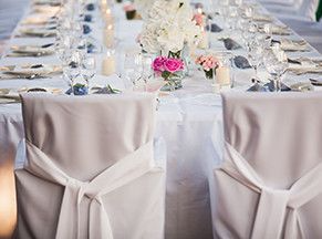 Una mesa larga con muchos vasos y flores encima.