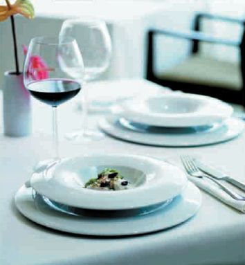 Una mesa con platos y copas de vino sobre ella.