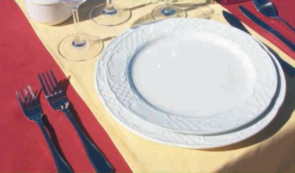 Una mesa con platos, tenedores, cuchillos y copas de vino.