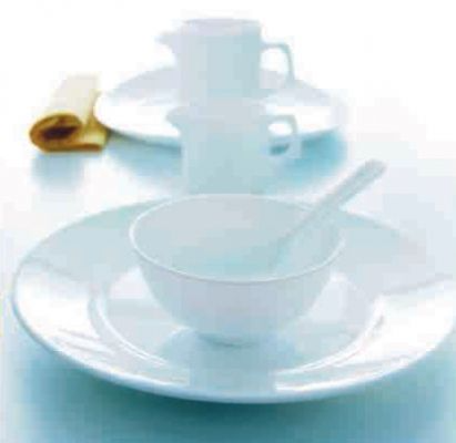 Un plato blanco con un cuenco y una cuchara encima.