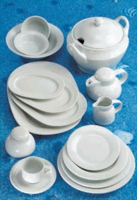 Un montón de platos y cuencos blancos sobre una superficie azul.