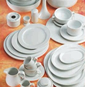 Un montón de platos y cuencos blancos sobre una mesa.