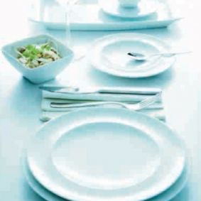 Una mesa con platos, utensilios y un cuenco de comida.