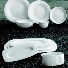 Un montón de platos y cuencos blancos sobre una mesa.