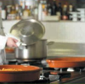 Una persona está cocinando en una estufa con ollas y sartenes encima.