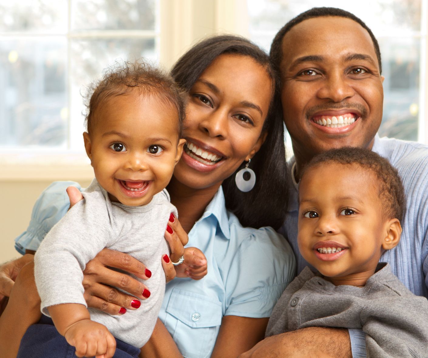 Smiling family of four sitting together on a couch indoors