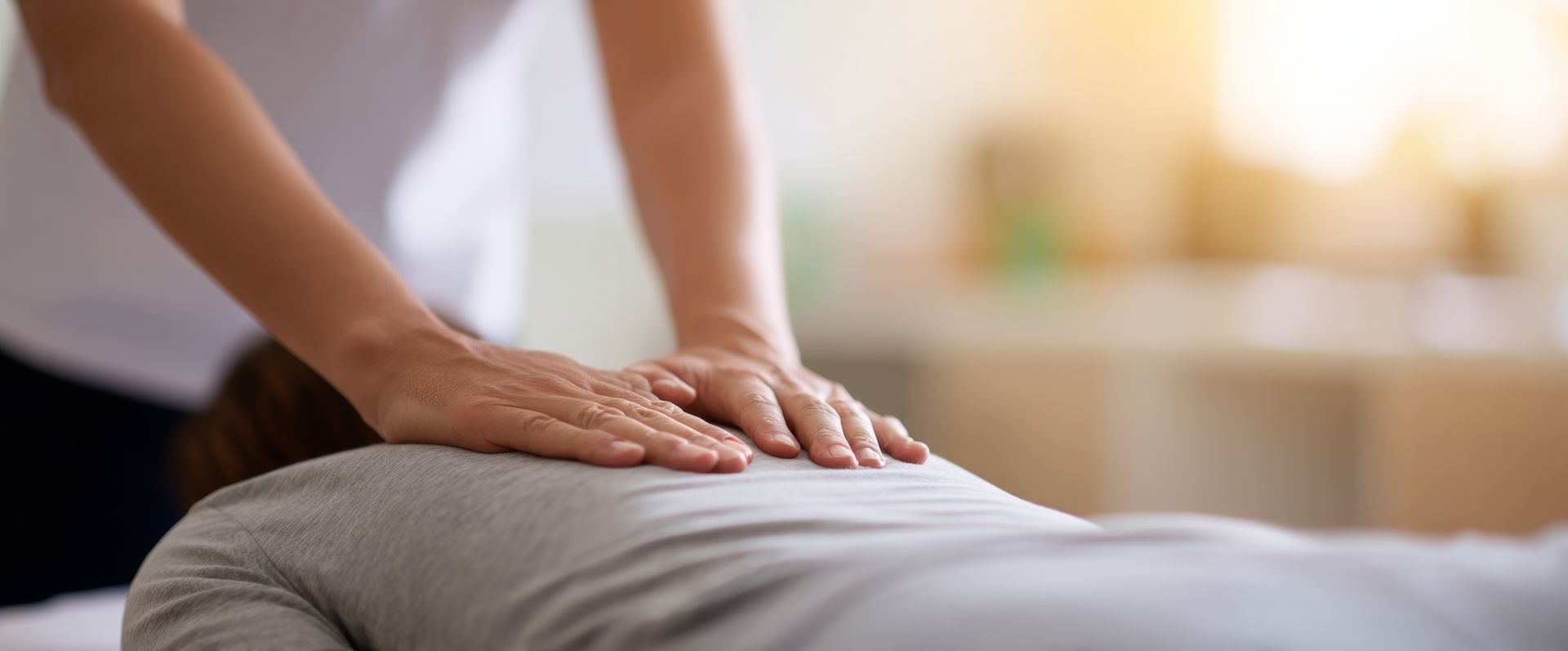 Des mains appuient sur le dos d'une personne lors d'un massage dans une pièce à l'éclairage tamisé.