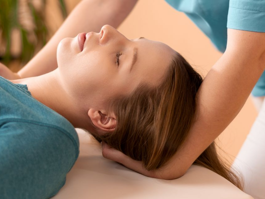 Une personne allongée sur une table de massage, les mains soutenant la tête et l'air serein.