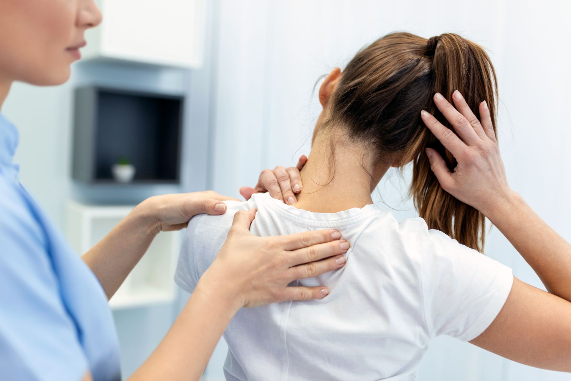 Une ostéopathe examine le cou et l'épaule d'un patient en clinique.