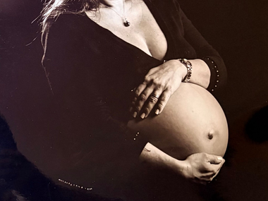 Un ours en peluche repose sur le ventre d'une femme enceinte, ses mains caressant doucement le ventre.