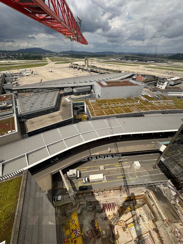 Ein rot-weisser Offshore-Kranarm ragt über eine gelbe Ölplattform, die von einem ruhigen blauen Meer unter sonnigem Himmel umgeben ist.