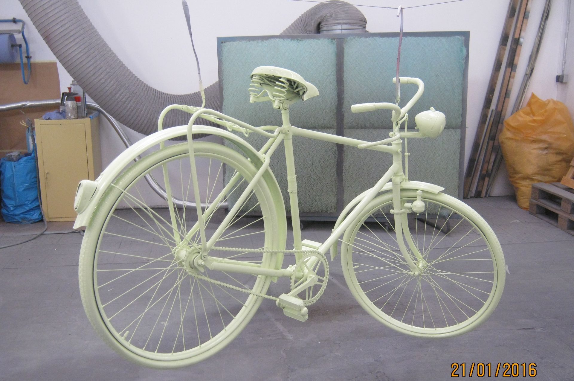 Mintgrüner Fahrradprototyp in einer Werkstatt, von der Seite betrachtet.