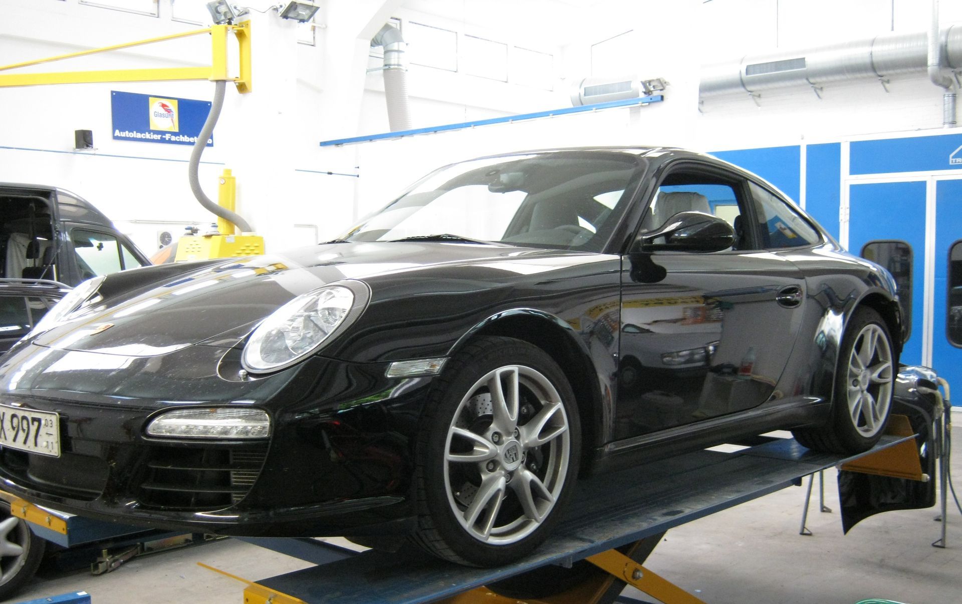 Schwarzer Sportwagen auf einer Hebebühne in einer Autowerkstatt