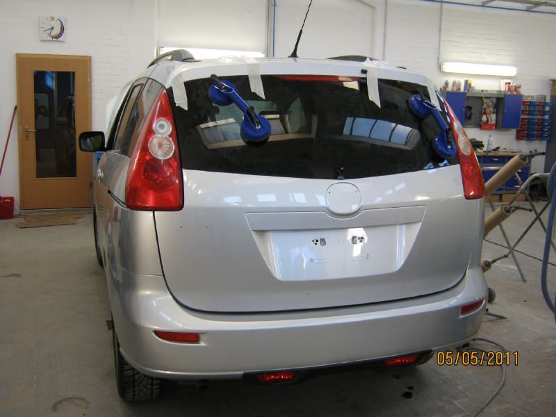 Ein silberner Schrägheckwagen steht in einer Garage, die Heckklappe ist geöffnet und blaue Gurte sind im Inneren sichtbar.