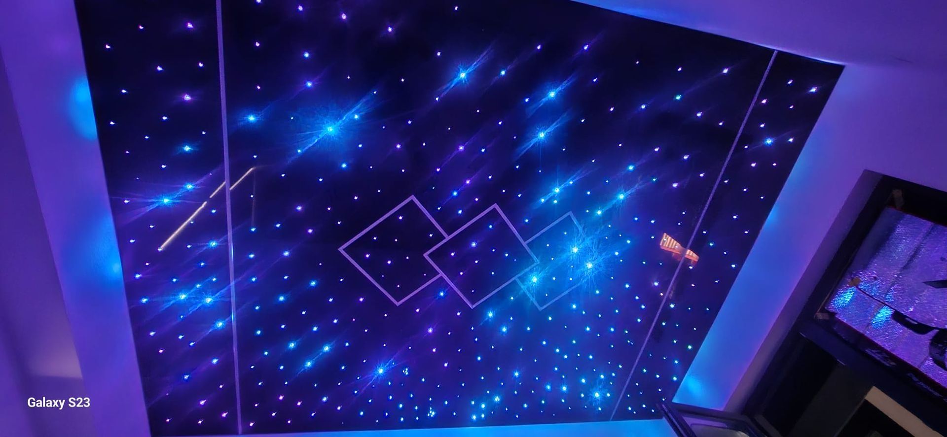 Gemütliches Wohnzimmer mit braunem Ledersofa, dunkelgrauer Wand mit Kunstwerken und einsehbarem Essbereich.