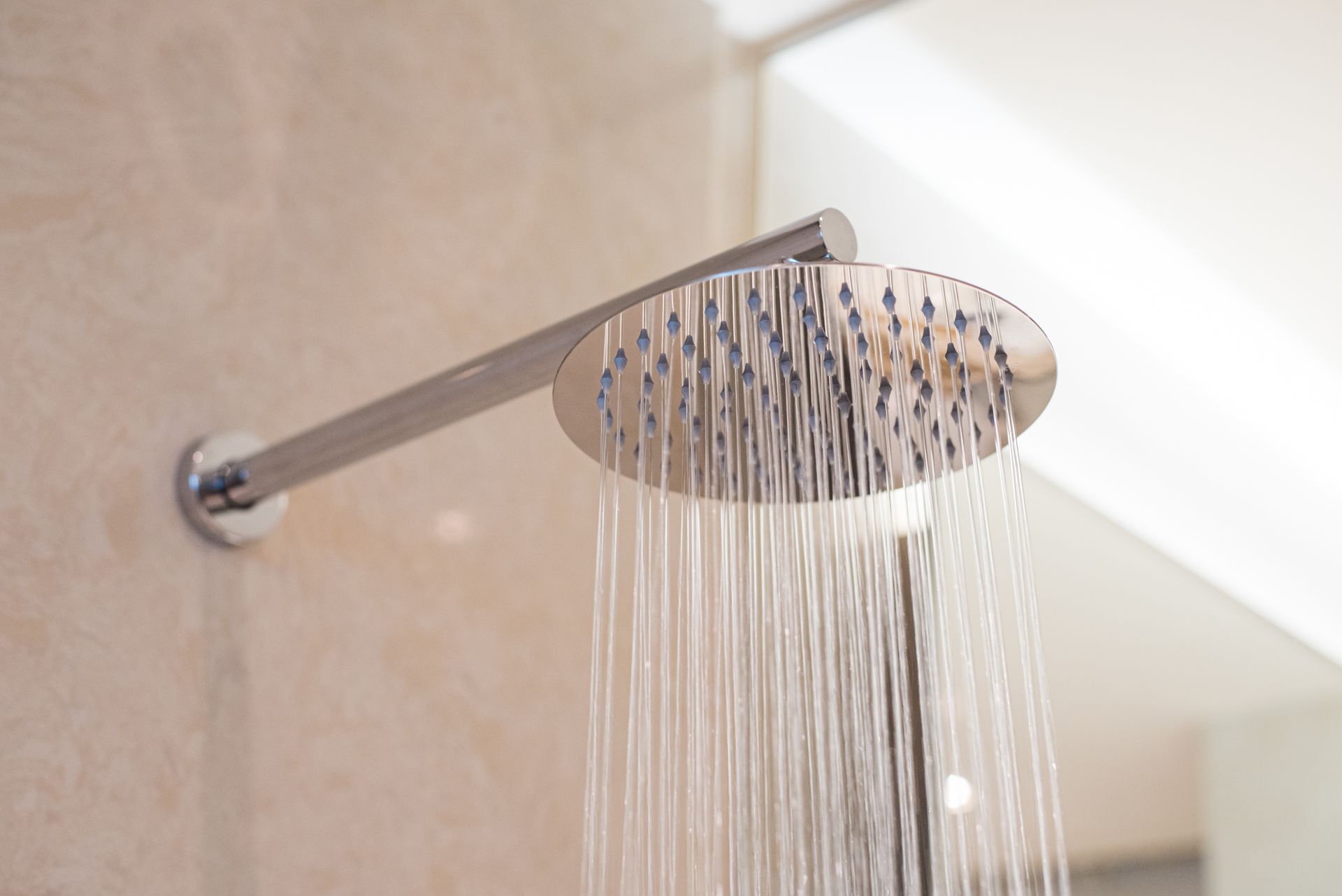 Un gros plan d'une pomme de douche dans une salle de bains avec de l'eau qui en sort.