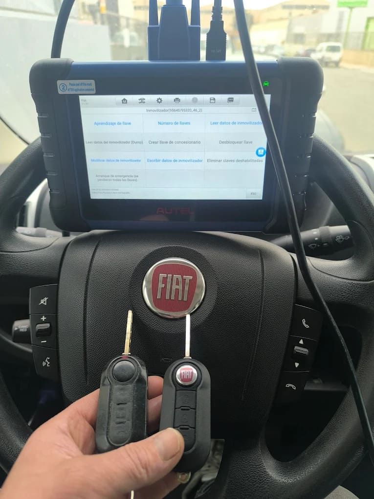 Una persona sostiene un par de llaves delante del volante de un Fiat.