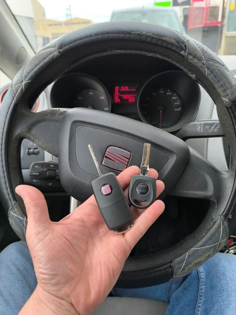 Una persona sostiene una llave de coche delante de un volante.