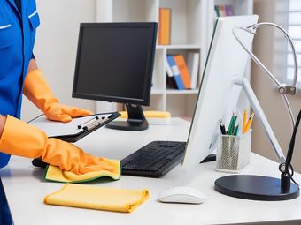 Agent d'entretien qui nettoie un bureau avec des ordinateurs
