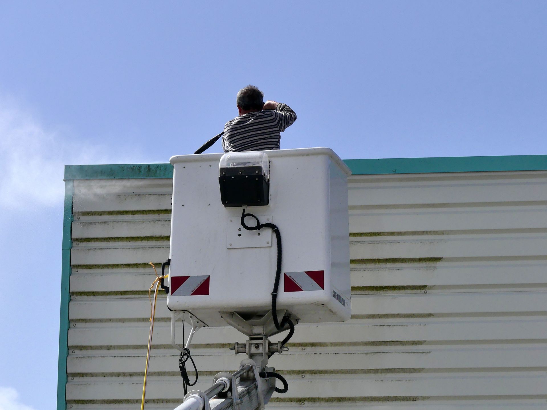 Nettoyage en cours d'un bardage métallique avec une nacelle et un jet à haute pression