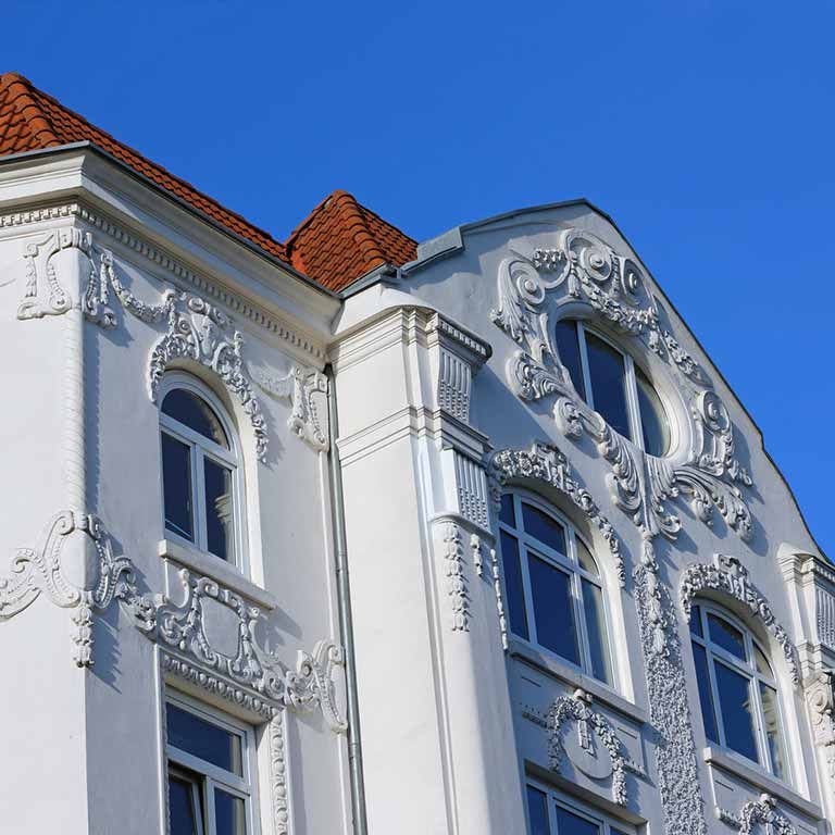 Ein weißes Gebäude mit einem roten Dach hat viele Fenster