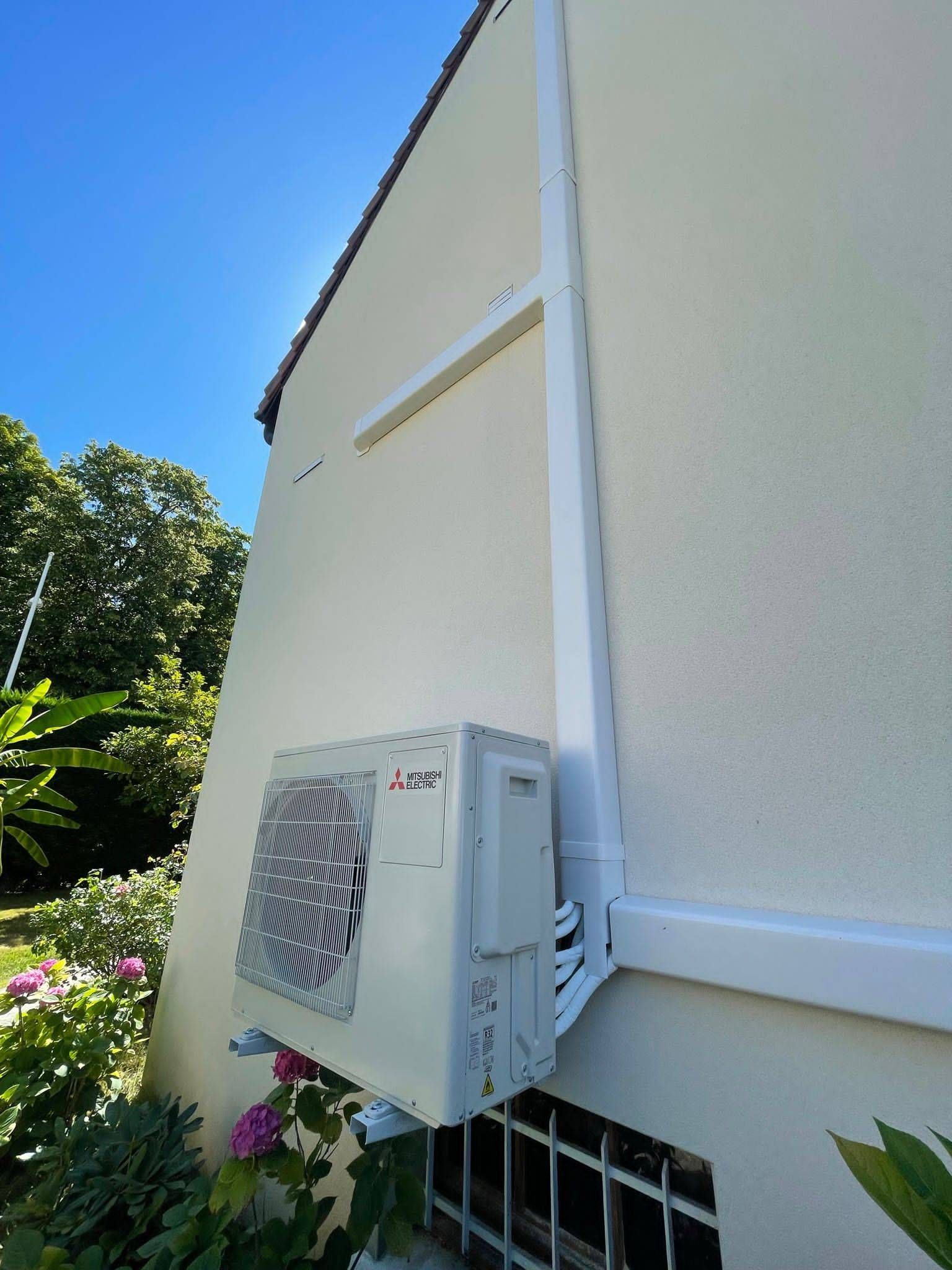Maison avec des panneaux solaires sur le toit au coucher du soleil, bordée de haies verdoyantes au premier plan