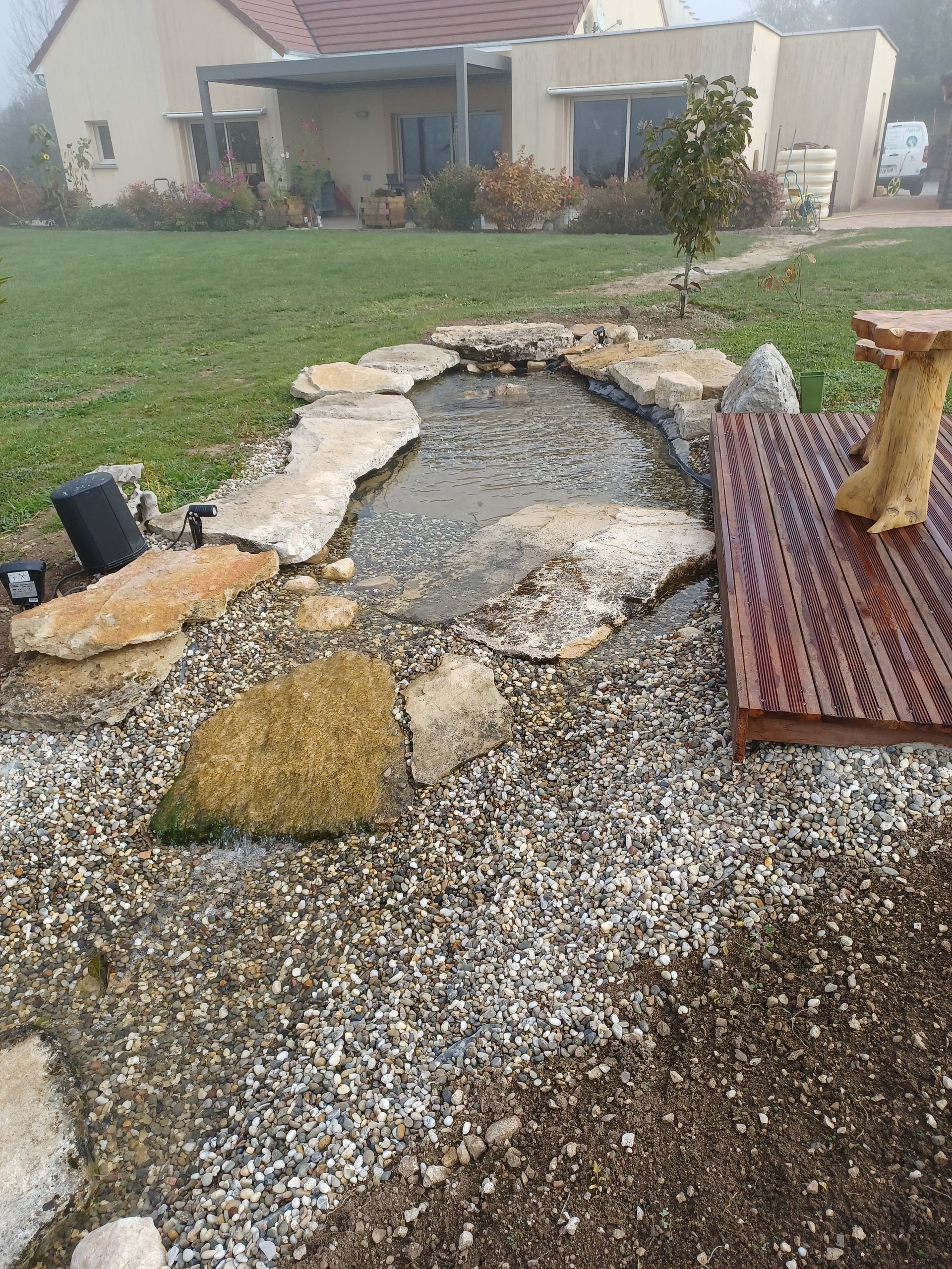 Un petit bassin entouré de pierres devant une maison