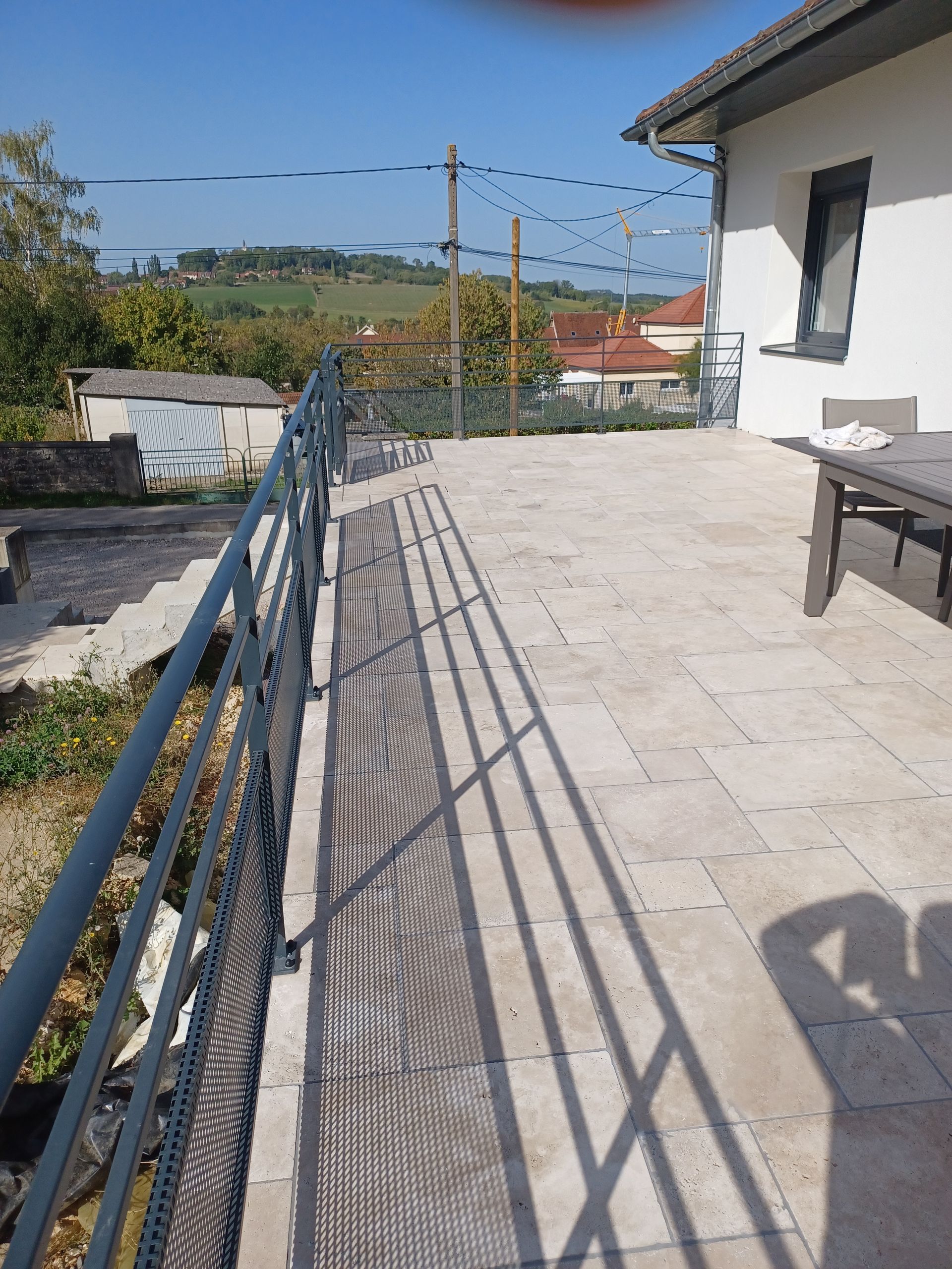 Une terrasse dallée d'où on voit une colline au loin