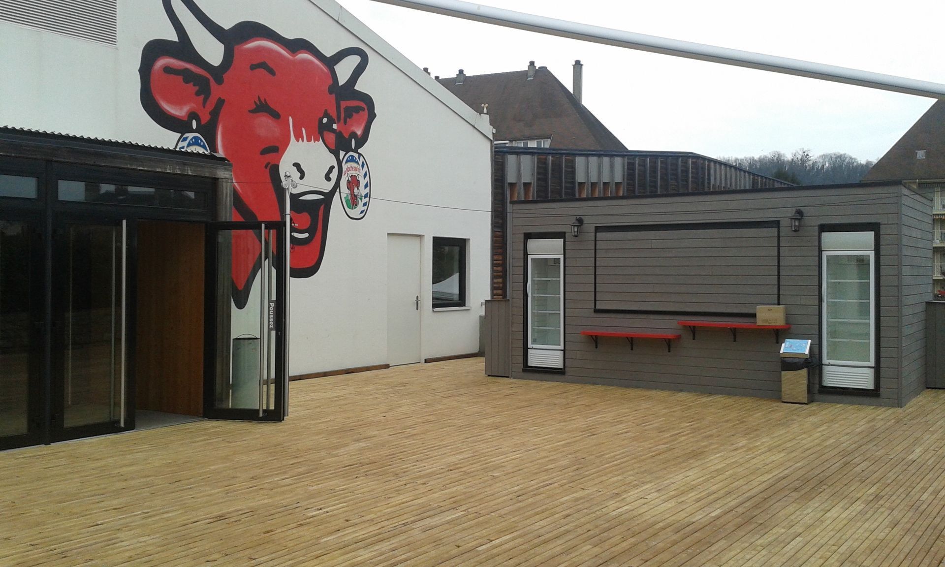Un mur avec un dessin de la marque Vache Qui Rit devant une terrasse en bois