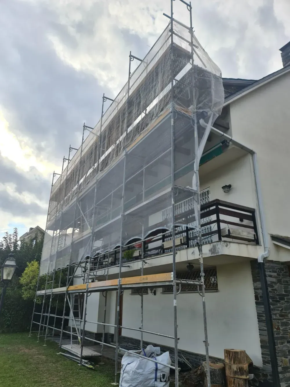 Dos limpiadores de ventanas descienden en rápel por el costado de un edificio alto y moderno bajo un cielo azul claro.