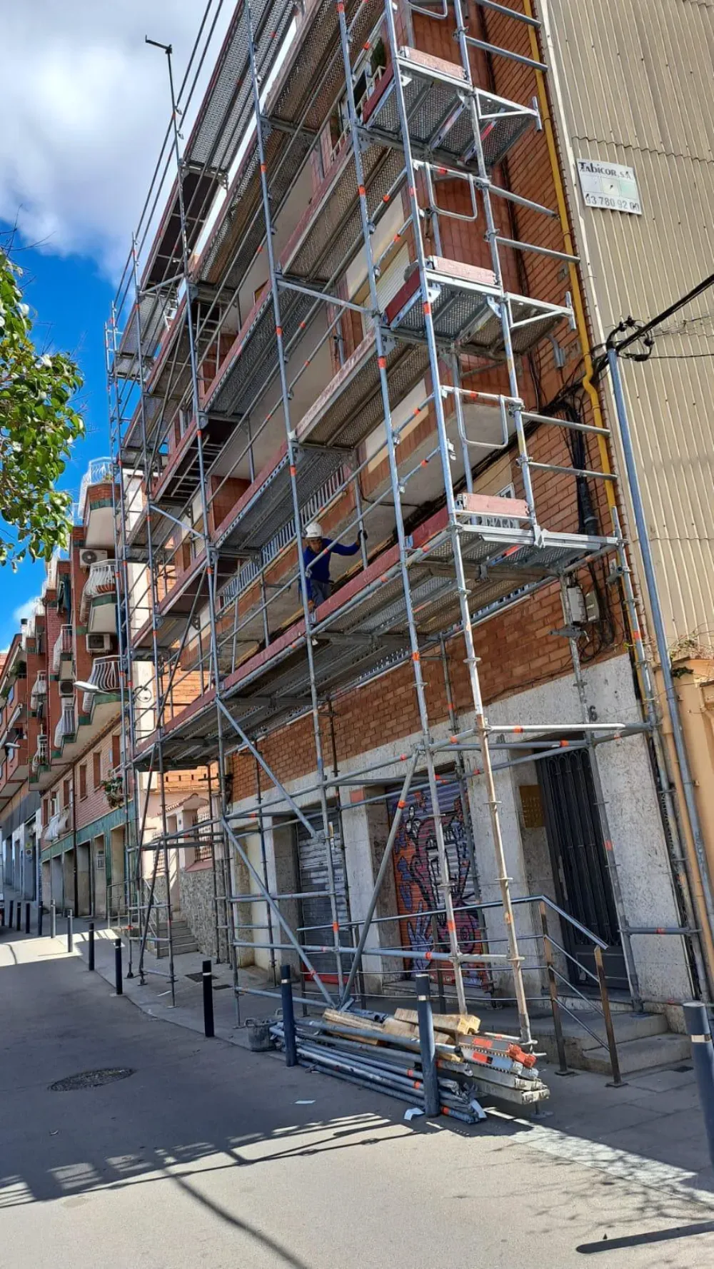 Dos limpiadores de ventanas suspendidos de cuerdas limpiando la fachada de un edificio alto.