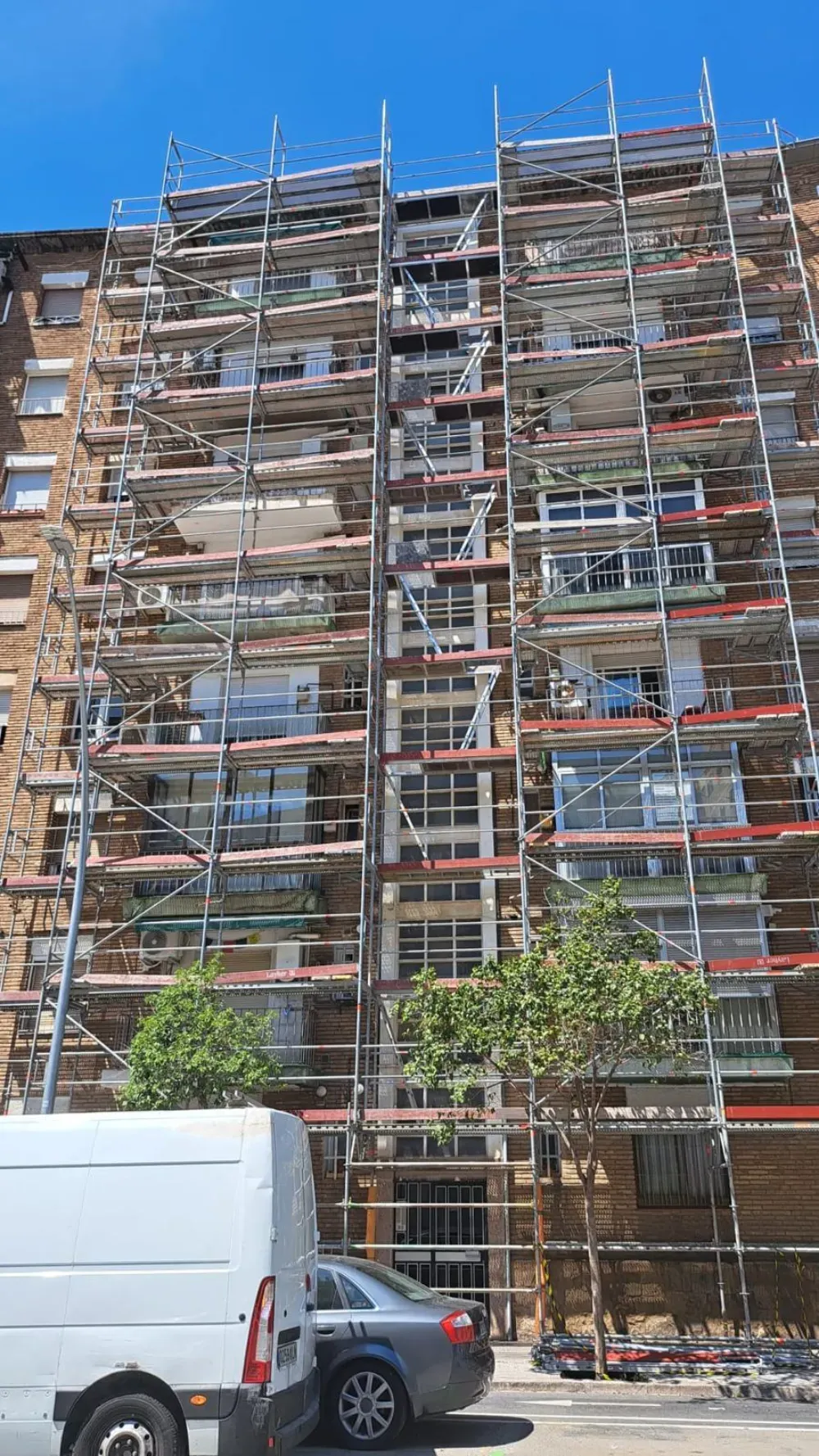 Limpiadores de ventanas en el lateral de un edificio alto; uno limpia las ventanas, el otro las estabiliza.