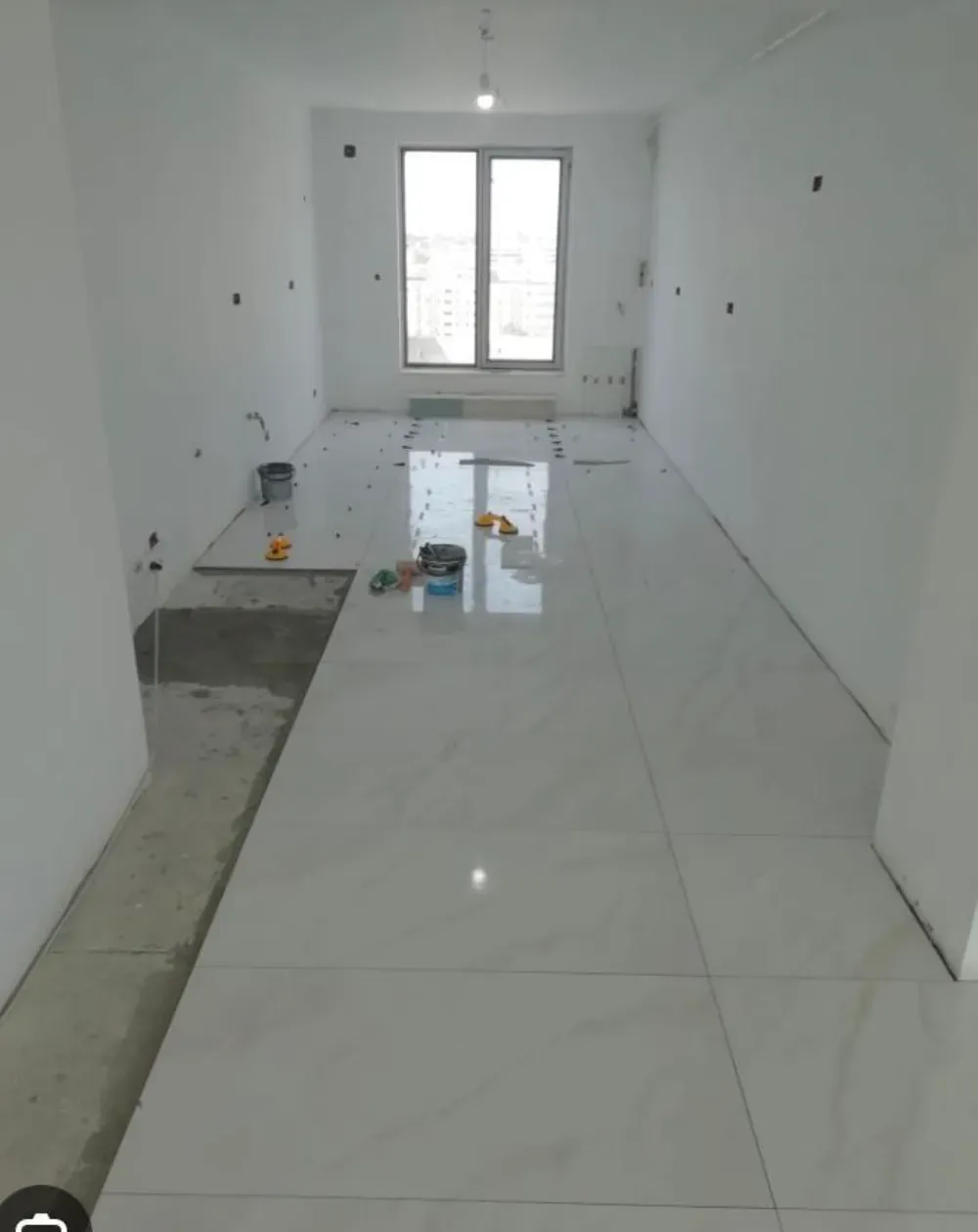 Hombre pintando una habitación con una pistola pulverizadora de pintura; las paredes están medio pintadas en varios tonos.