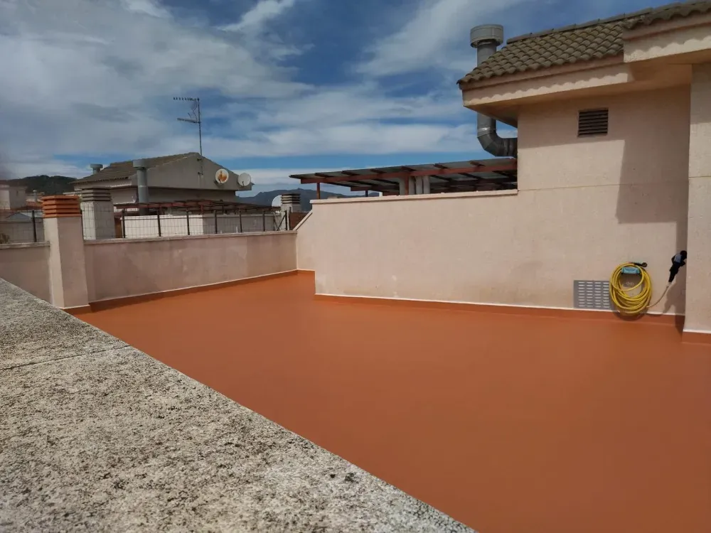 Interior de una habitación en construcción, con paredes expuestas, escombros en el piso y luz natural.
