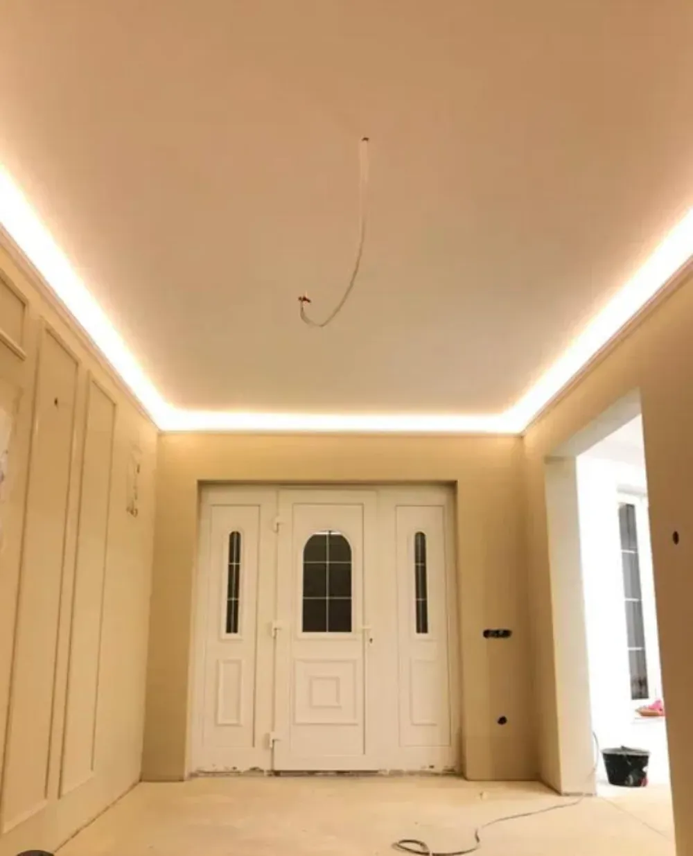 Habitación vacía con herramientas para pintar; escalera, latas de pintura y bote de basura.