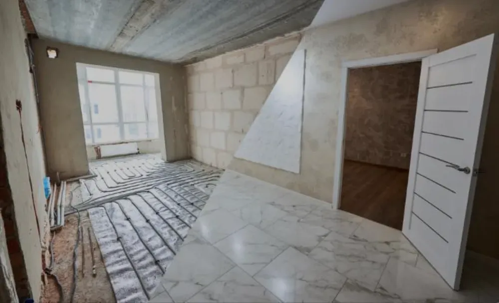 Habitación en construcción, con paredes grises y blancas, cableado y un deshumidificador verde.