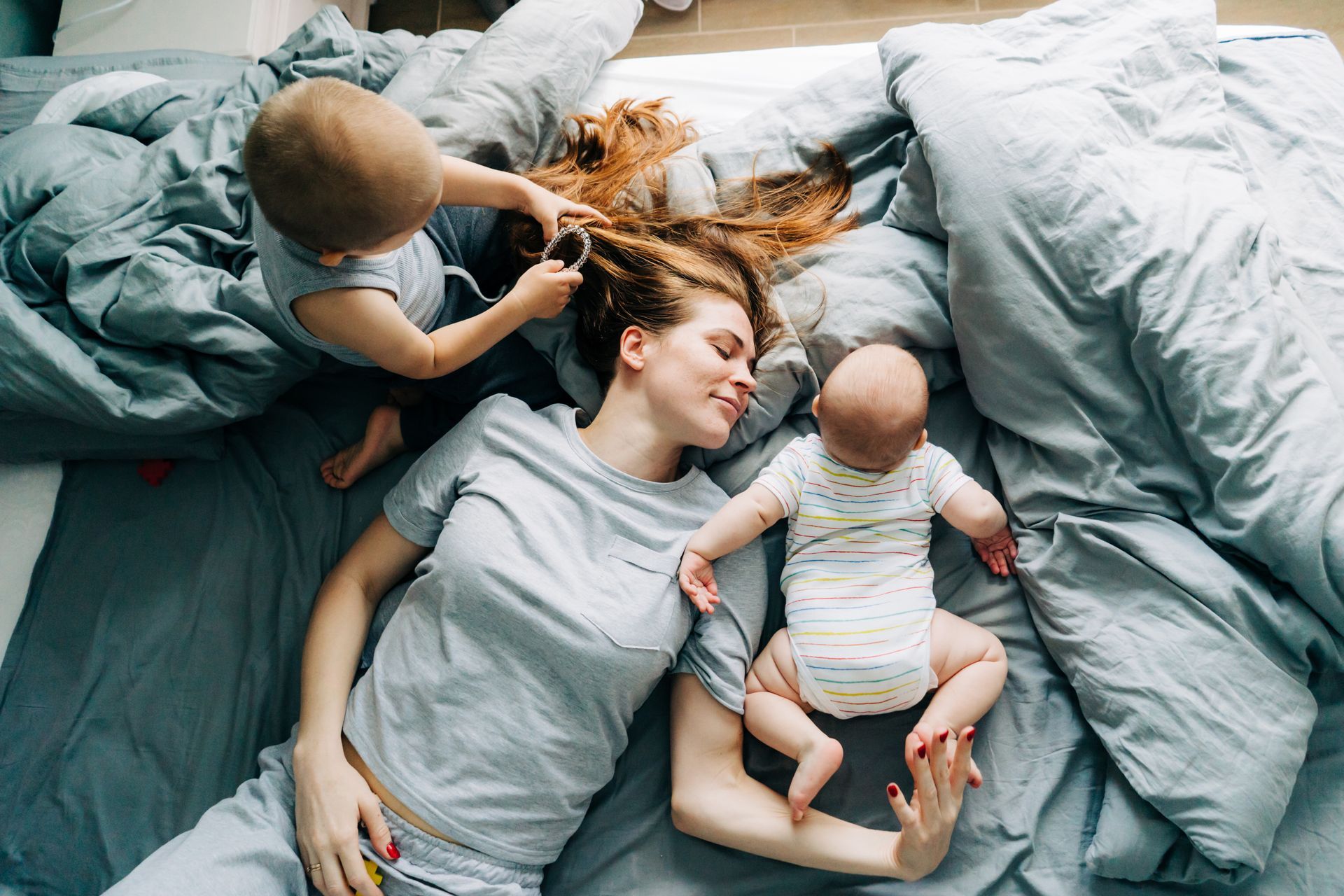 Femme avec ses deux enfants sur un lit