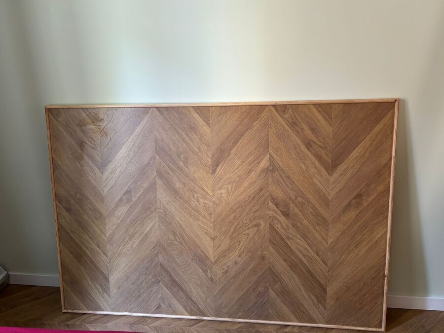 Cabecero de madera con estampado de espiga sobre pared verde claro.