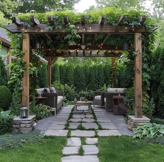 Pérgola de madera cubierta de enredaderas, sobre un patio de piedra con asientos al aire libre.