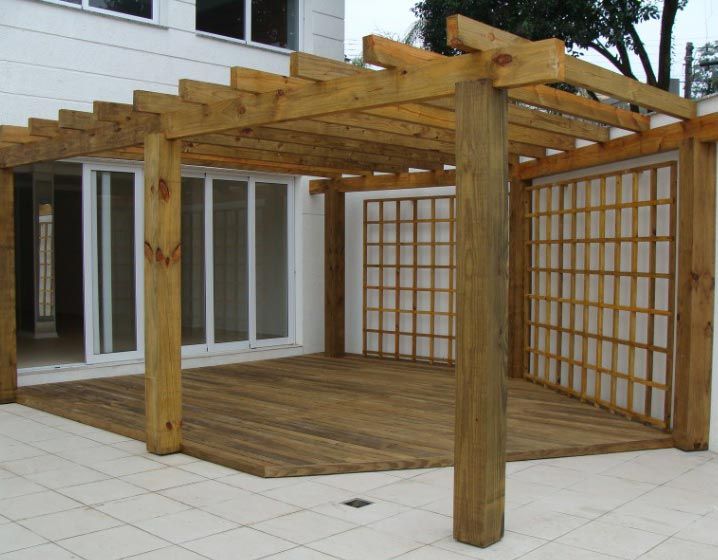 Pérgola de madera con laterales enrejados y cubierta, adyacente a puertas corredizas de vidrio.