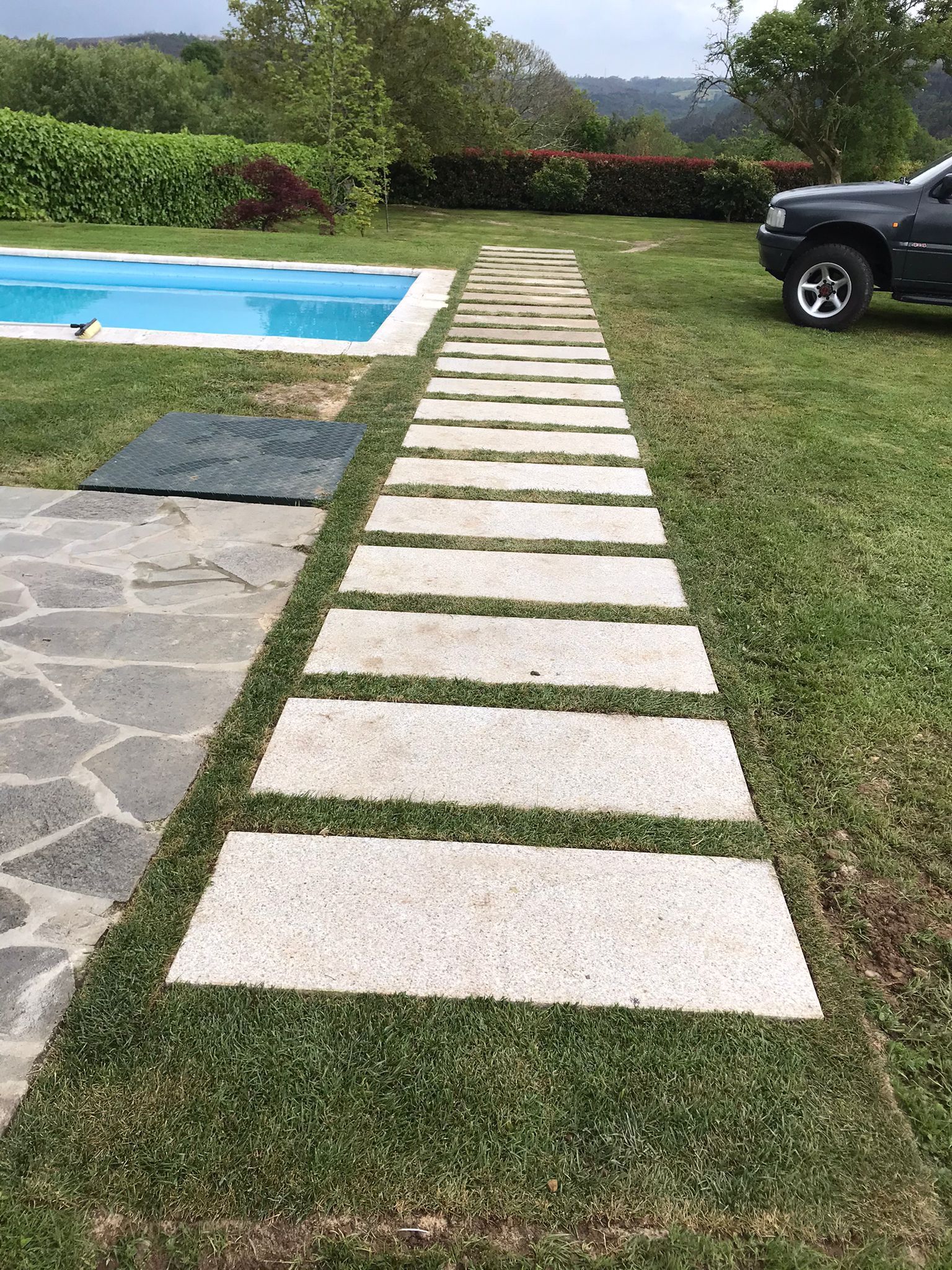 Un coche está aparcado al lado de la carretera al lado de una piscina.