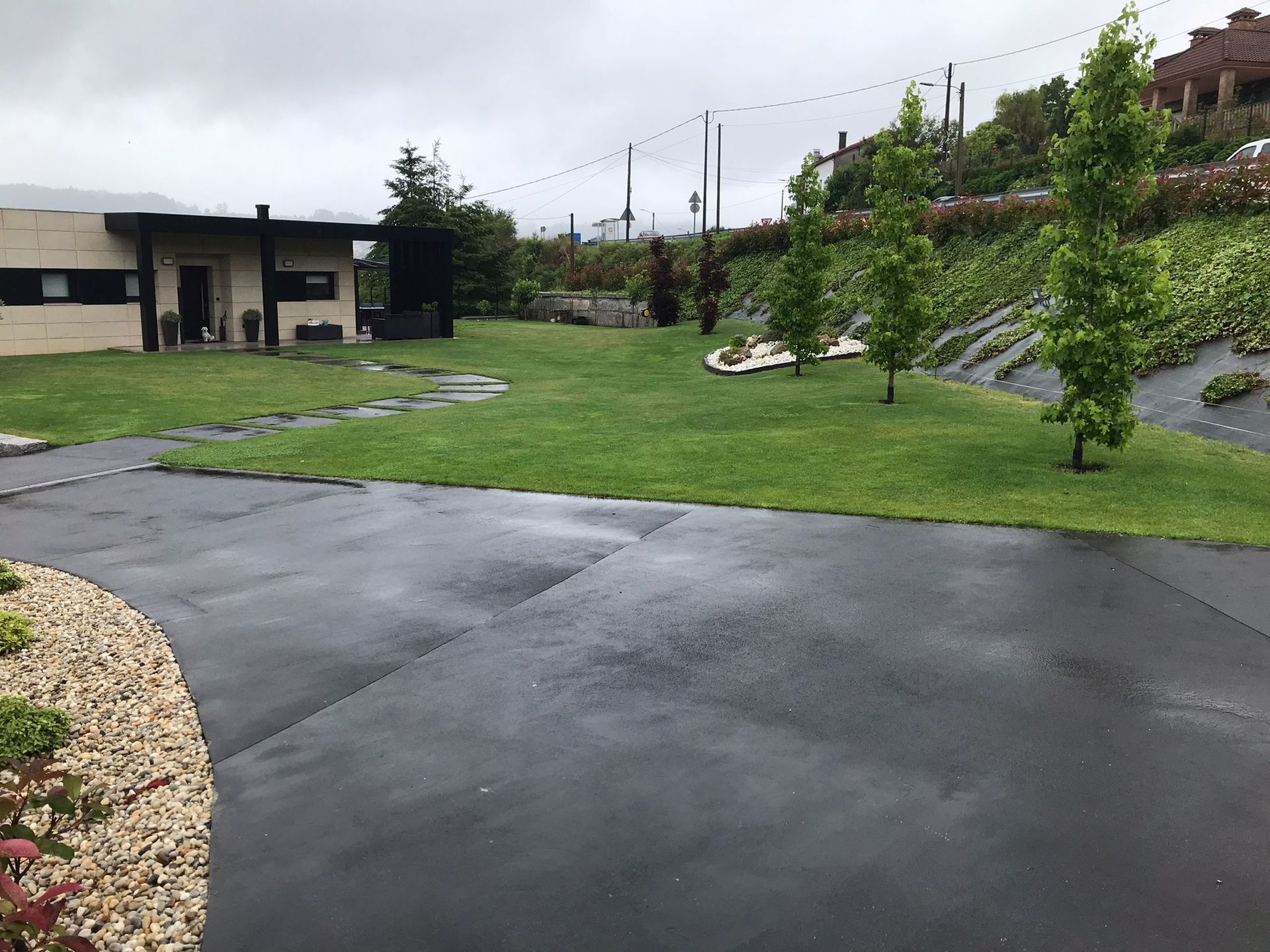 Un camino de entrada que conduce a una casa con un exuberante césped verde.