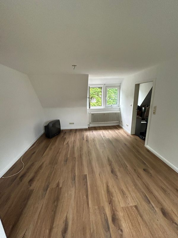 Ein Wohnzimmer mit Holzboden und weißen Wänden.