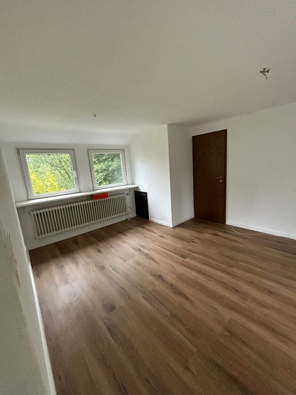 Ein großer leerer Raum mit Hartholzböden und einem Fenster.