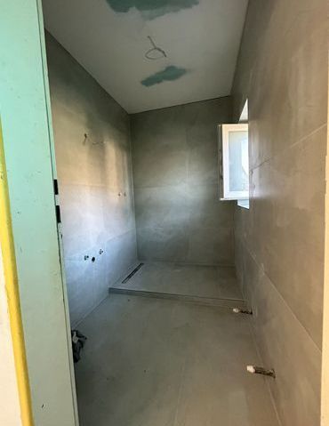 Ein im Bau befindliches Badezimmer mit Fenster und gefliesten Wänden.