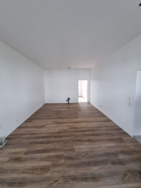 Ein großer leerer Raum mit Holzboden und weißen Wänden.