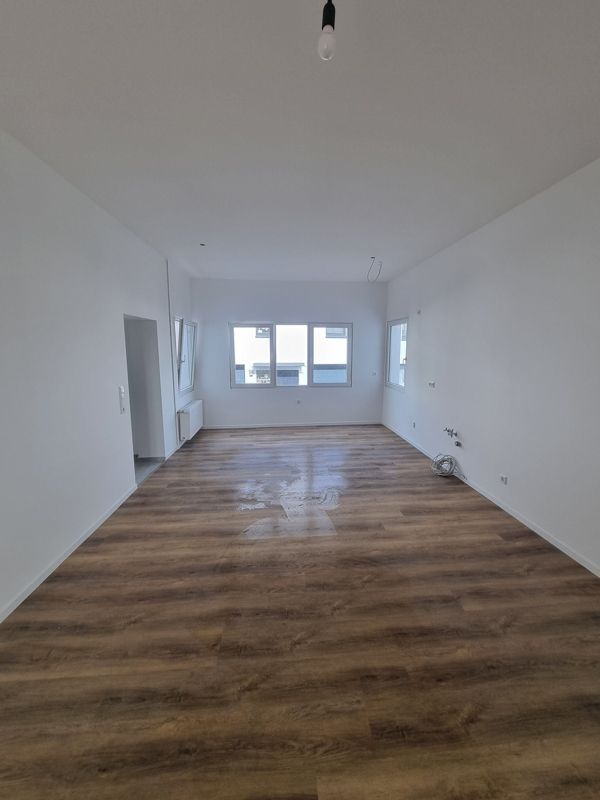 Ein großer leerer Raum mit Holzboden und weißen Wänden.