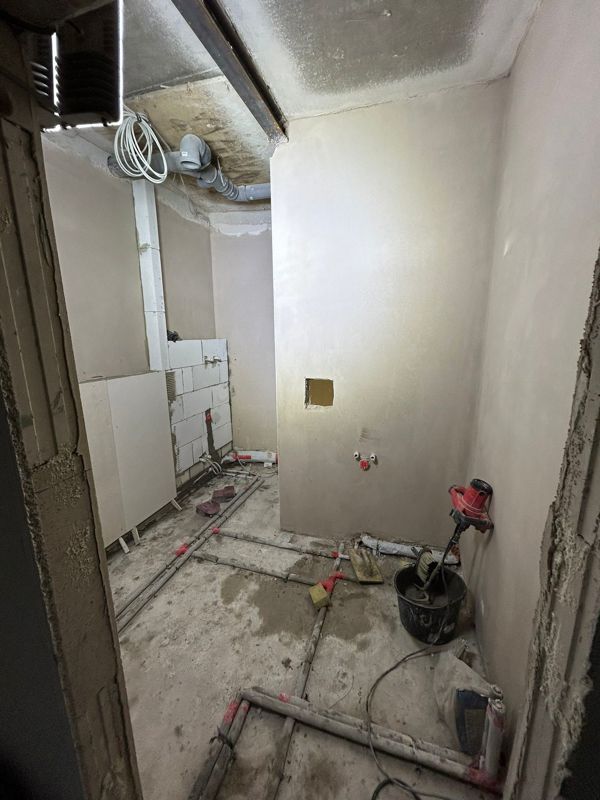 Ein im Bau befindliches Badezimmer mit einer Mischbatterie auf dem Boden.